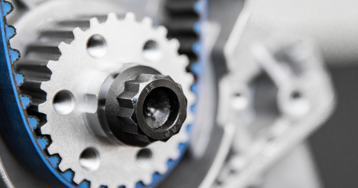 Detailaufnahme eines Zahnriemenrads mit schwarzer Befestigungsschraube in einer technischen Maschinen- oder Motorbaugruppe