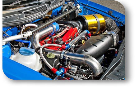 Detailaufnahme eines getunten Motorraums in einem blauen Auto mit Aluminium-Ladeluftrohren, Sportluftfilter und roten Motorbauteilen