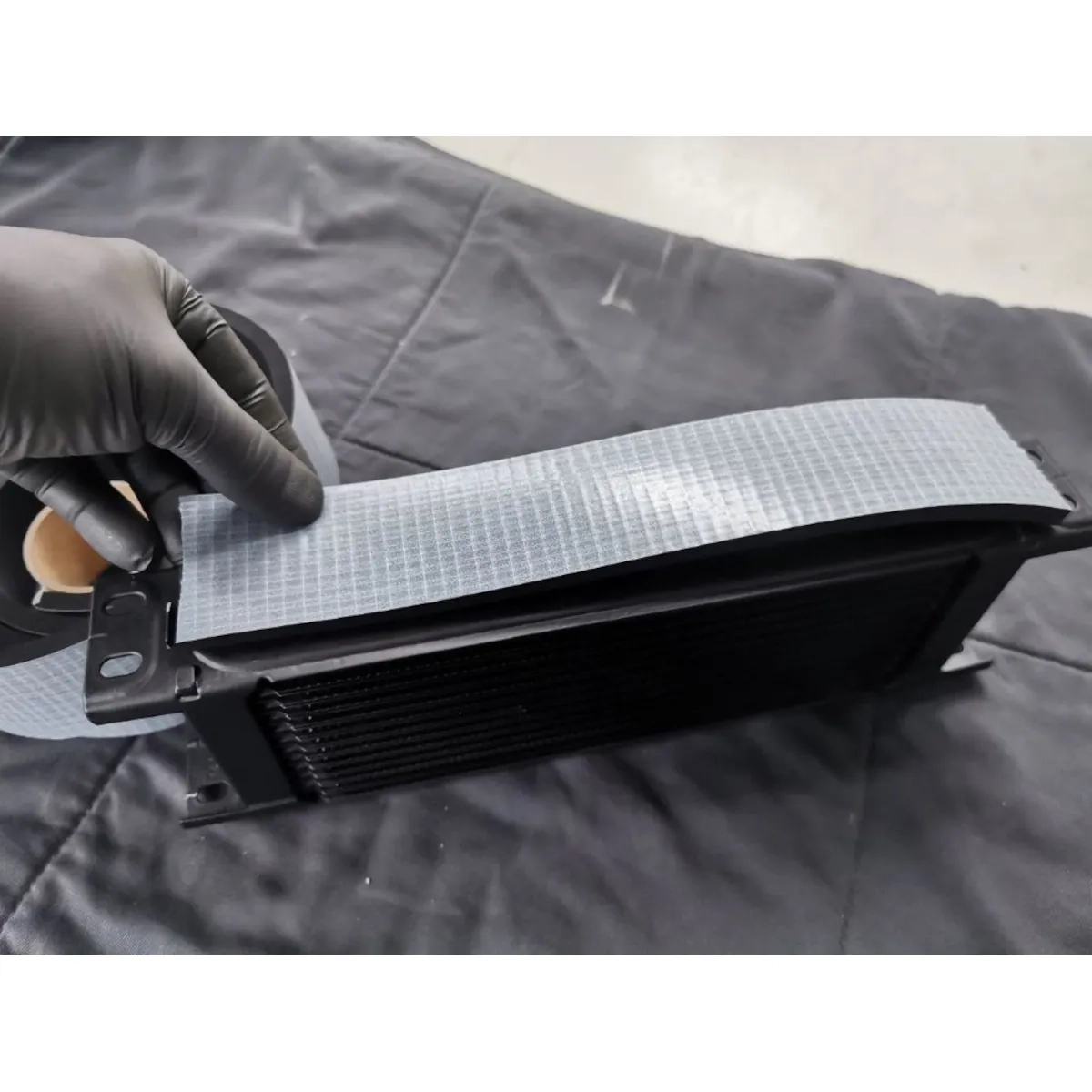 BAR-TEK® self-adhesive foam rubber chafing protection being applied to an oil cooler, used as chafing and vibration protection for lines and coolers, 50 x 6 mm, length 50 cm.